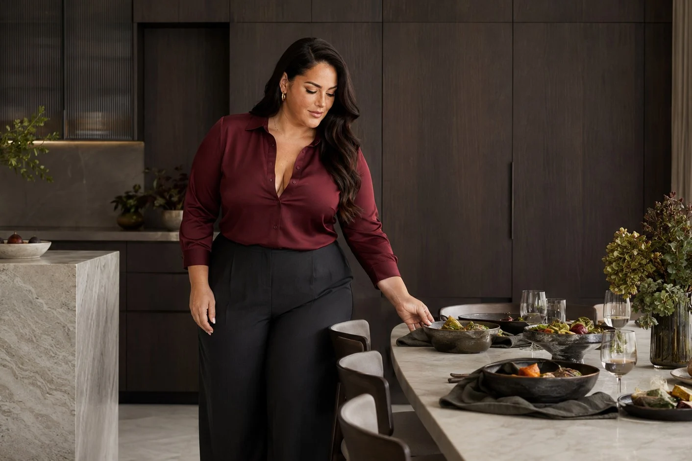 Nina setting a marble dining table in a burgundy silk shirt.