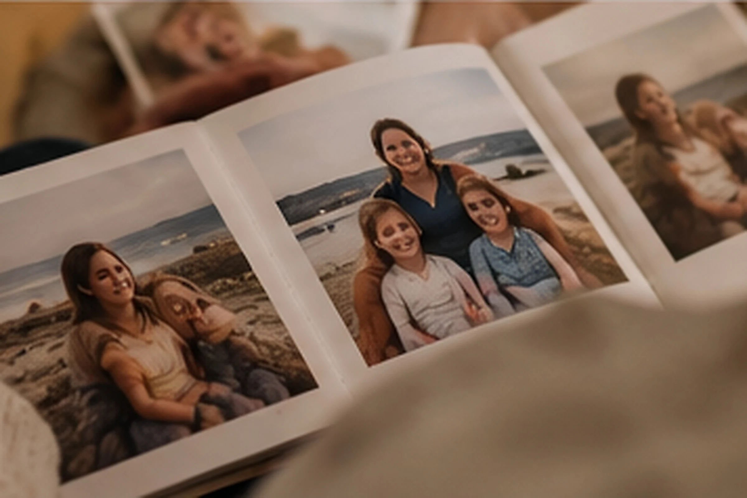An open photo album with pictures of a mother and her two daughters on a beach.